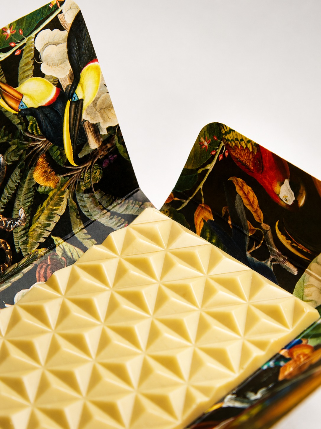 Detalle de tableta de chocolate blanco con relieve geométrico y envolvente ilustrada