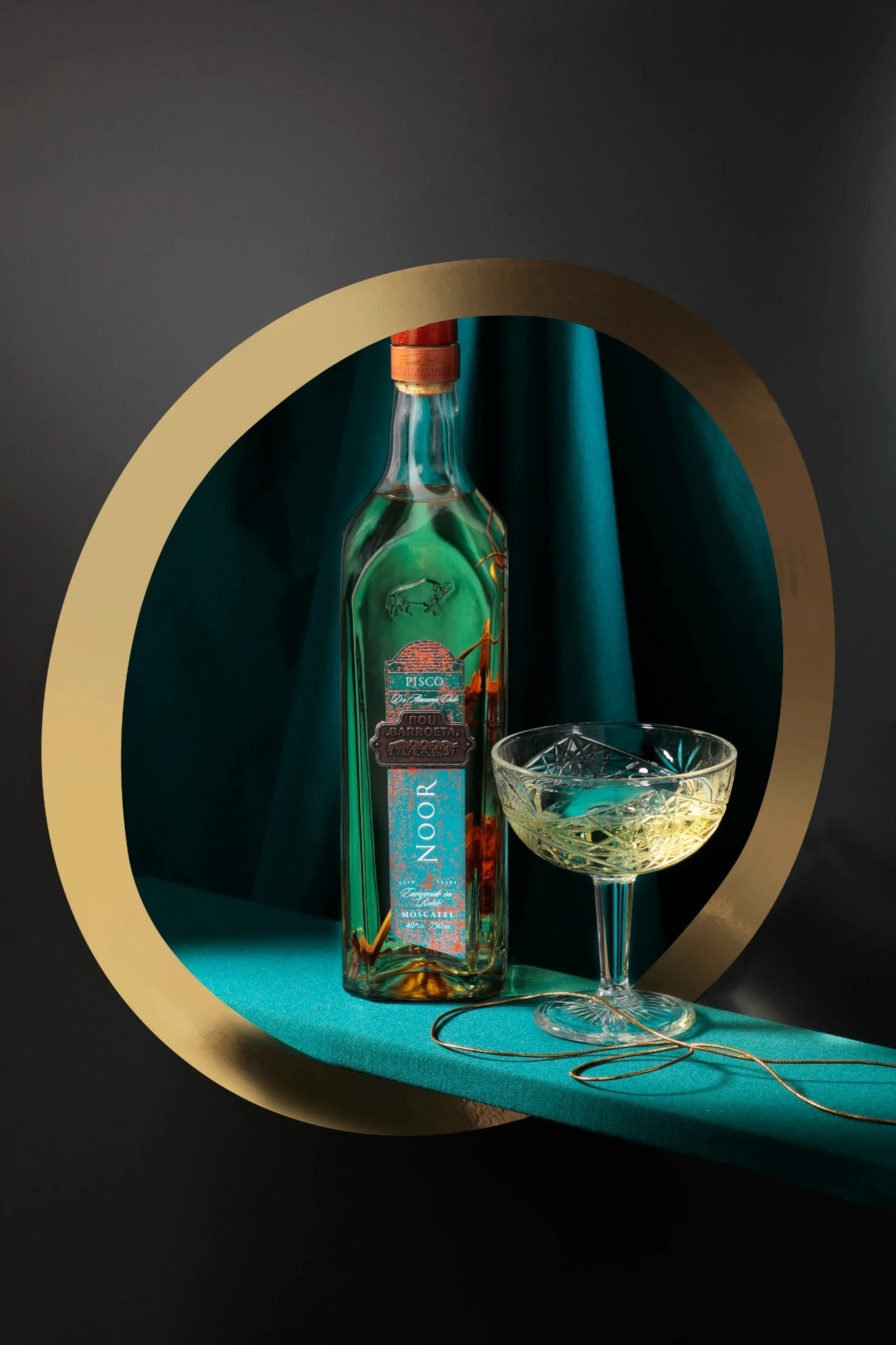 Bou Barroeta's Noor bottle next to a poured glass, on a turquoise background with a gold arch.