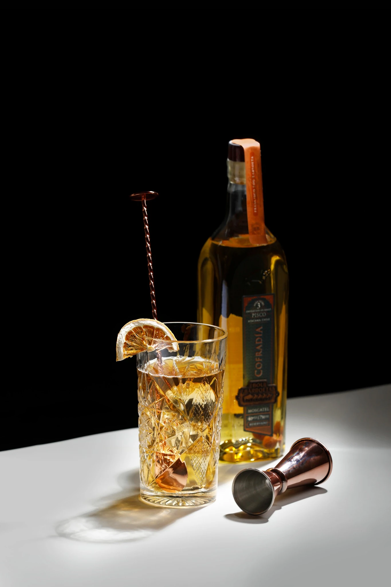 Cóctel preparado con pisco Cofradía de Bou Barroeta, con cítrico deshidratado y jigger de cobre.