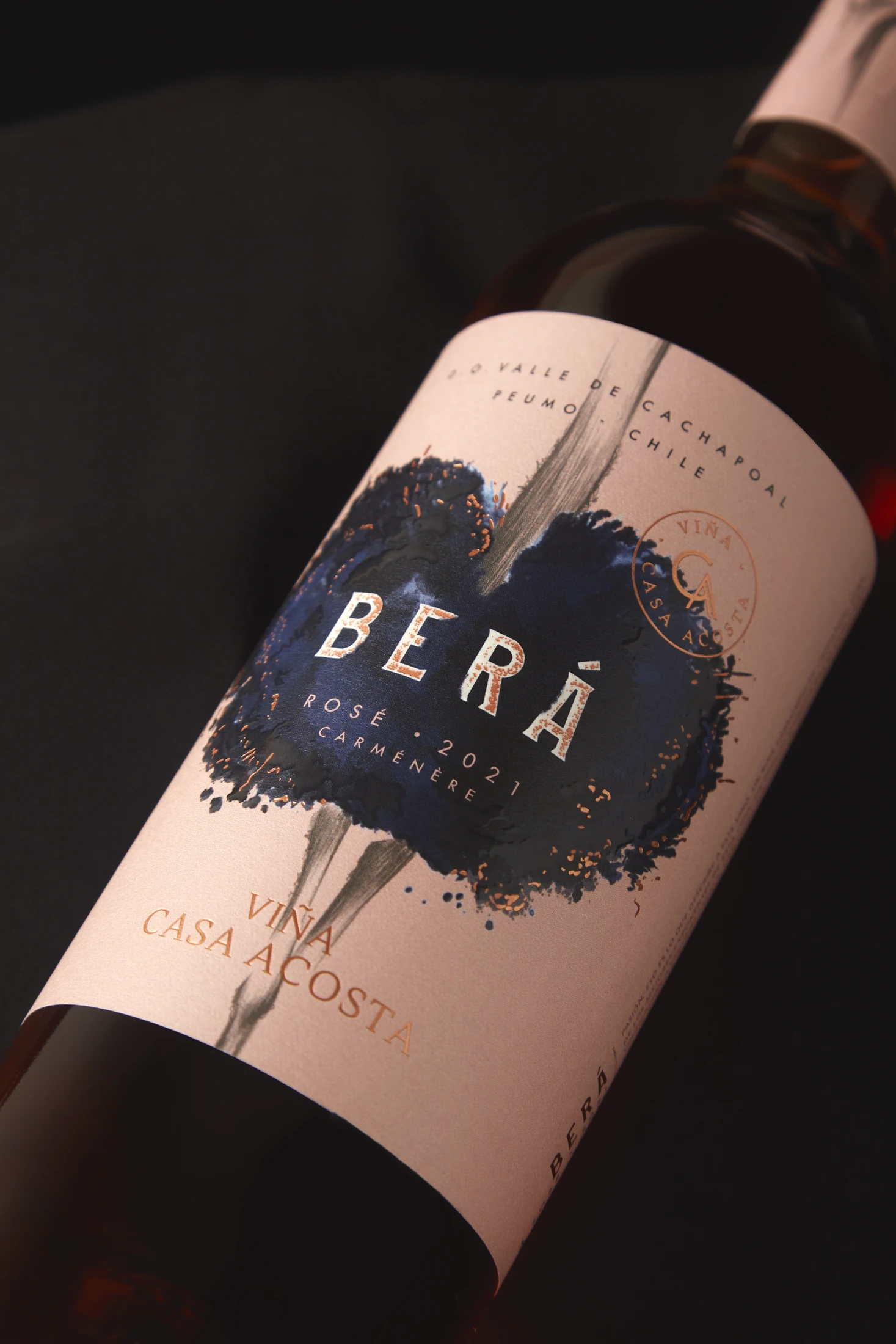 Detalle de la etiqueta Berá Rosé: mancha de tinta azul sobre papel blush, con el rosé visible a través del vidrio.