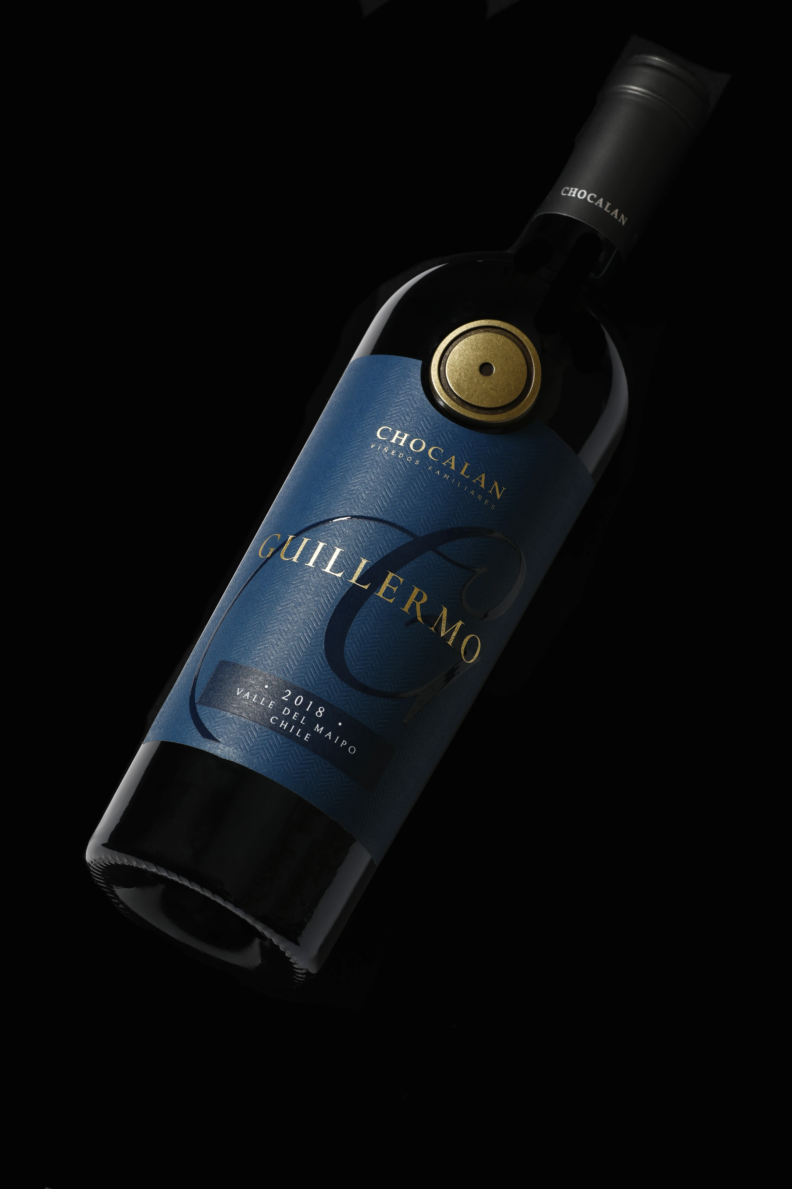 Botella Guillermo de Viña Chocalán con etiqueta azul profundo, monograma G y sello dorado.