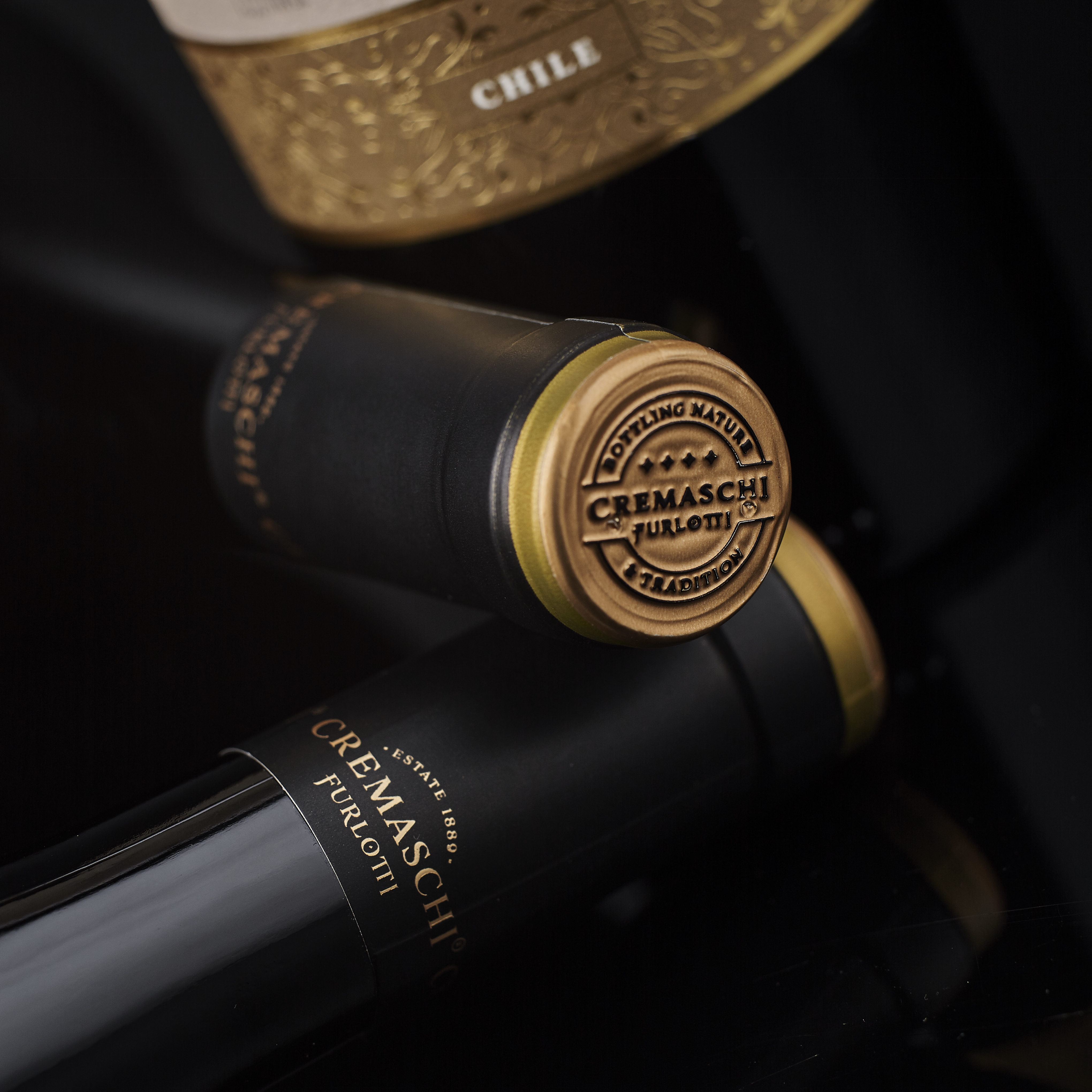 Detalle de cápsulas y sello Cremaschi Furlotti en botellas negras.