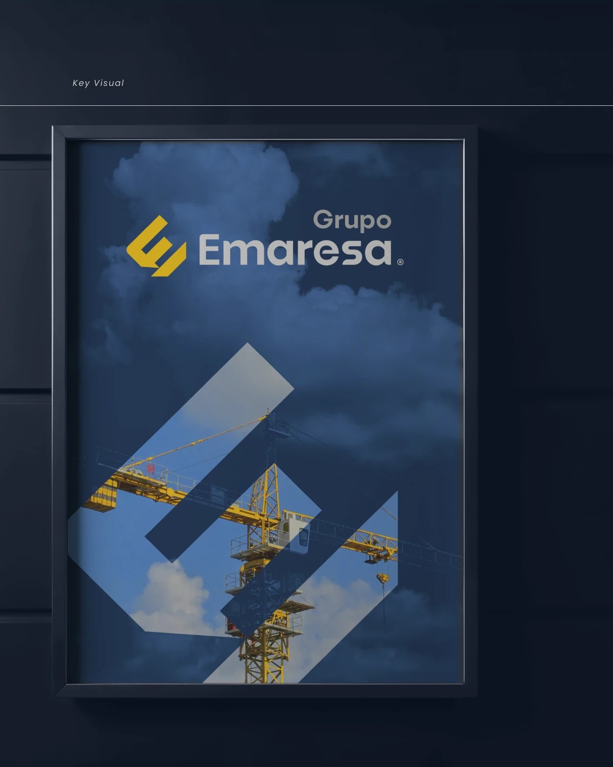 Key visual de Grupo Emaresa: isotipo E/M aplicado sobre una fotografía de grúa contra el cielo