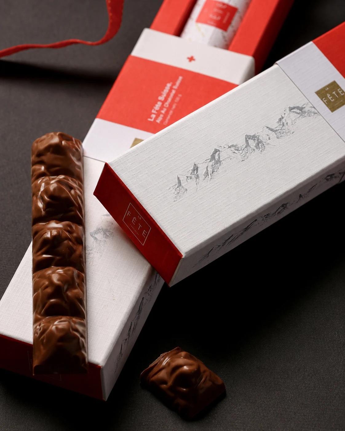 Barra de chocolate con textura de montaña 'Alps Au Chocolat Suisse' junto a su estuche blanco y rojo