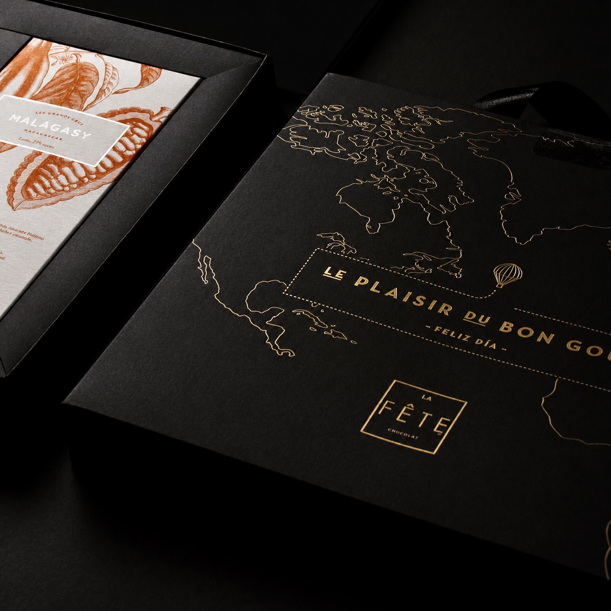 Detalle de una caja negra La Fête con mapa del mundo y textos estampados en folia dorada
