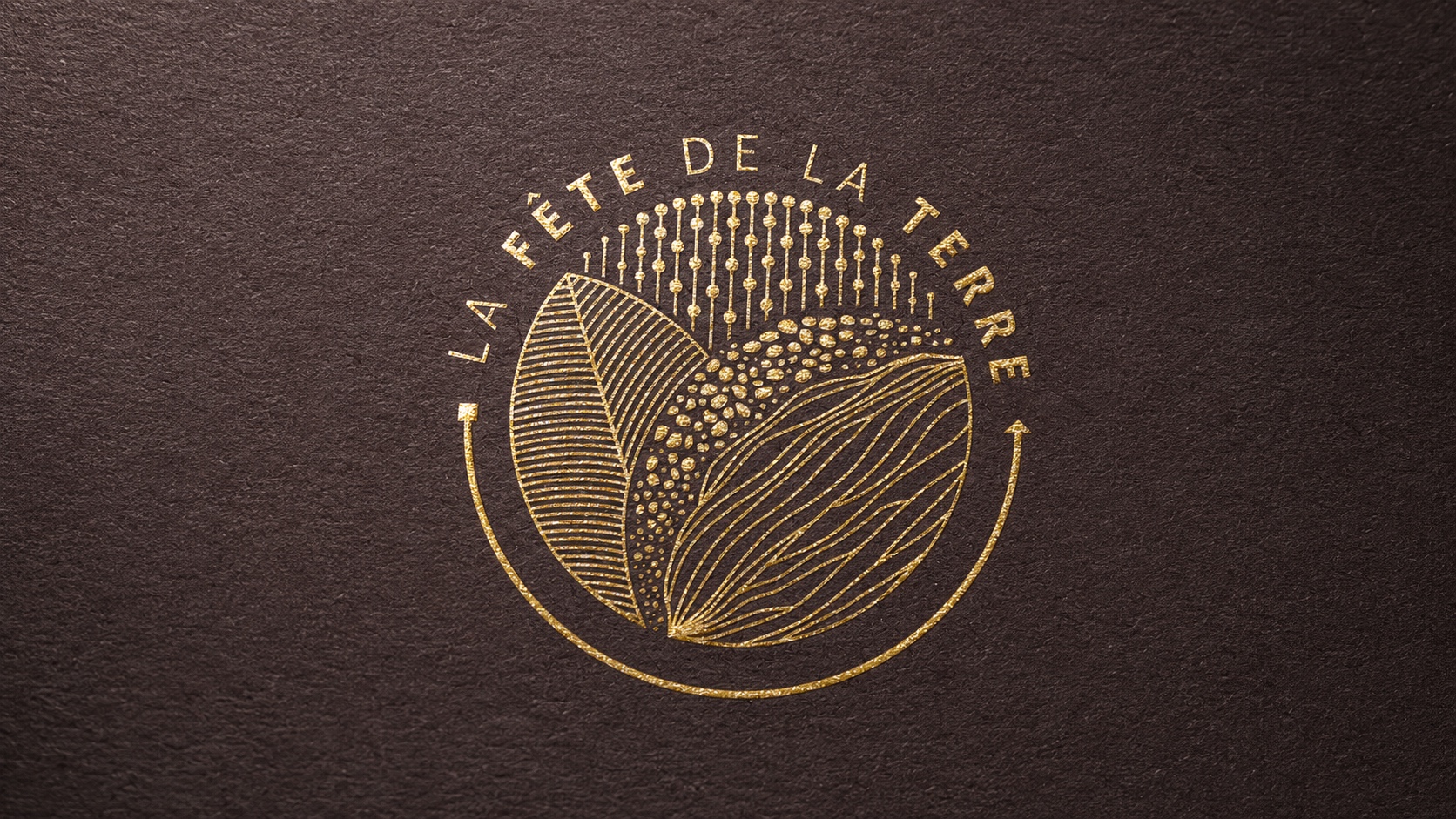 Emblema dorado de La Fête de la Terre estampado sobre una superficie café oscura con textura