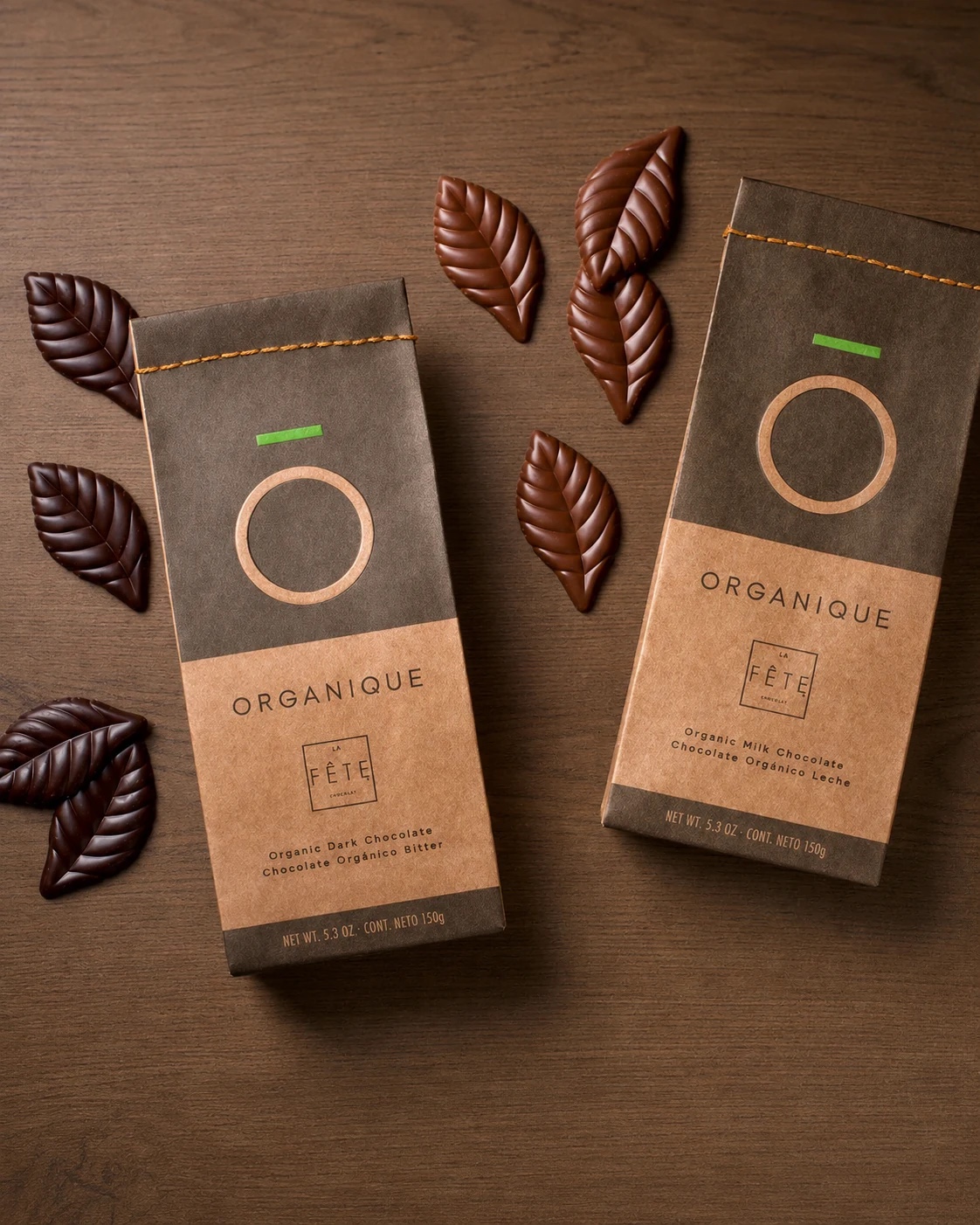 Cajas de barras de chocolate Organique de La Fête en kraft, junto a hojas de chocolate