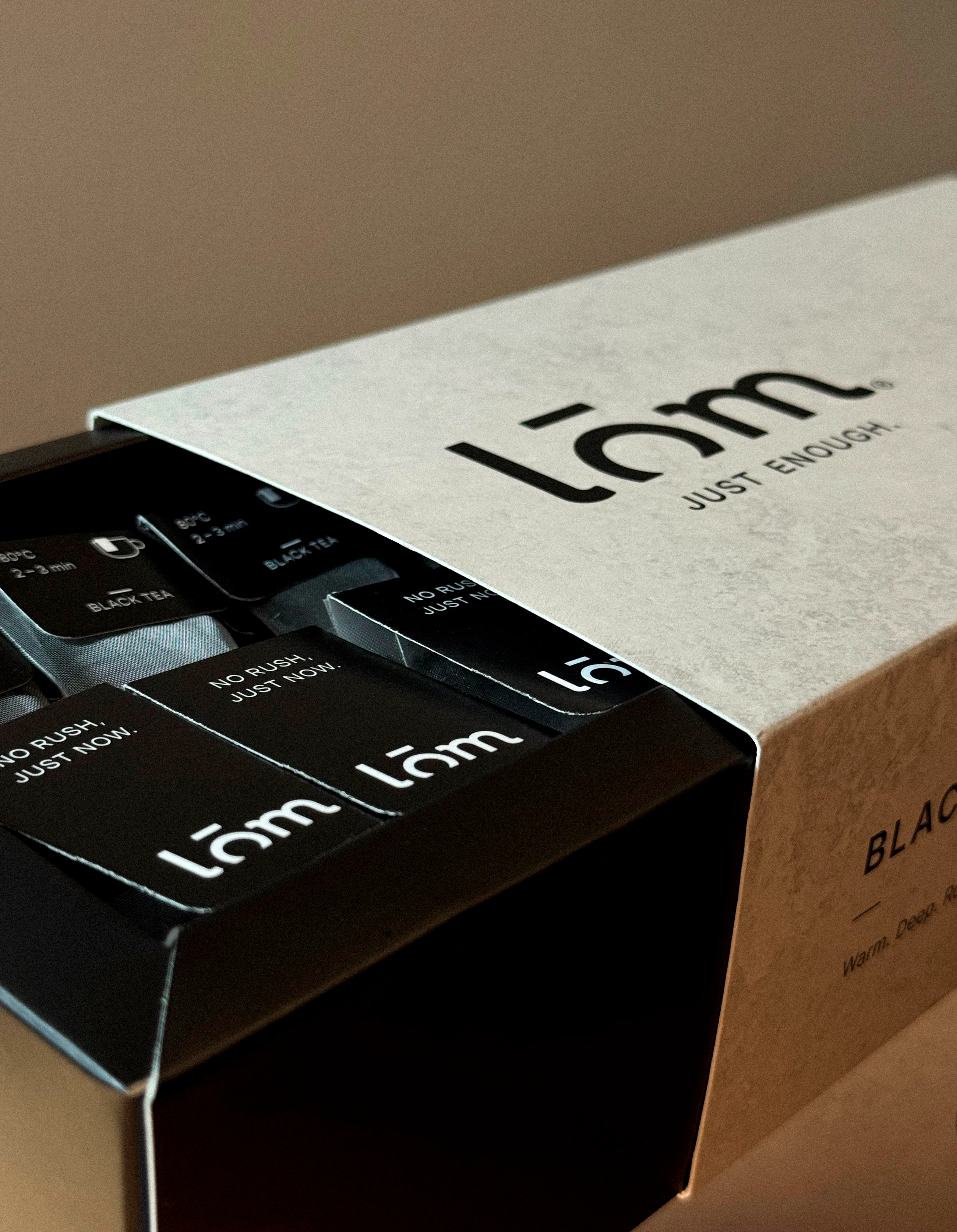Caja LŌM abierta con unidades individuales de té negro organizadas en su interior.