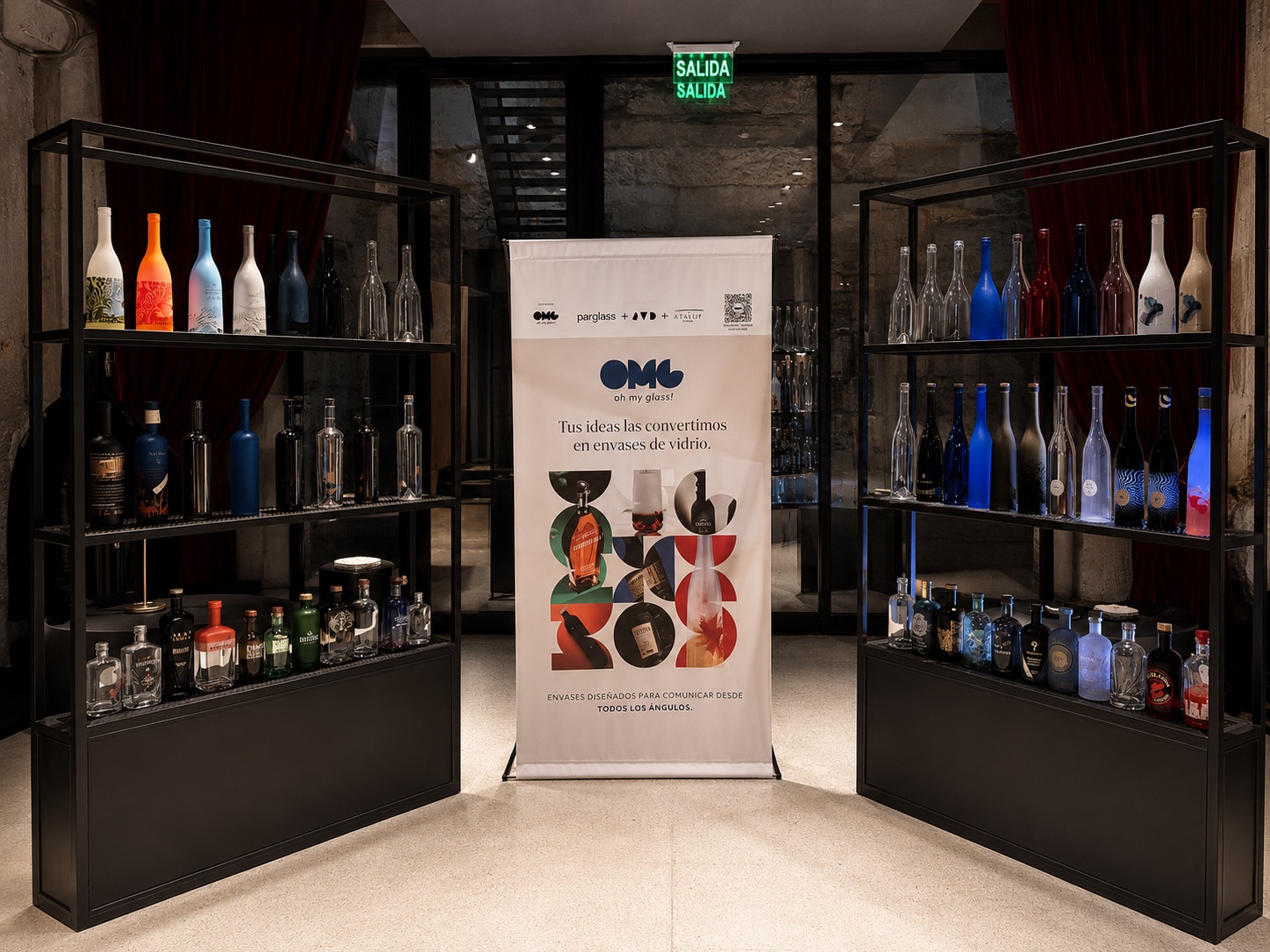 Stand de Oh My Glass con botellas de vidrio exhibidas y banner de la alianza Parglass + JVD Estudio