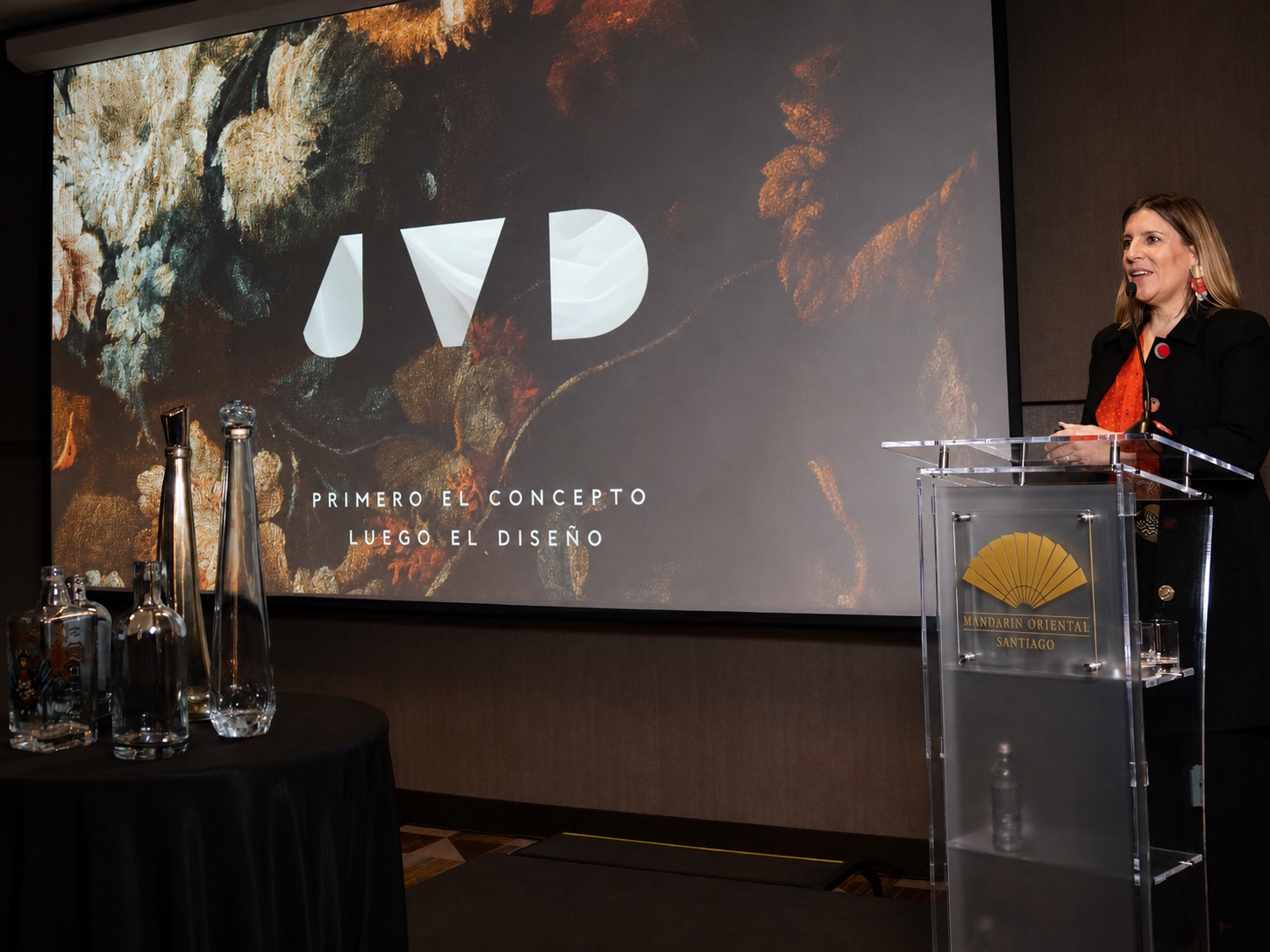 Presentación de JVD Estudio ante público, con proyección de la marca JVD y botellas exhibidas
