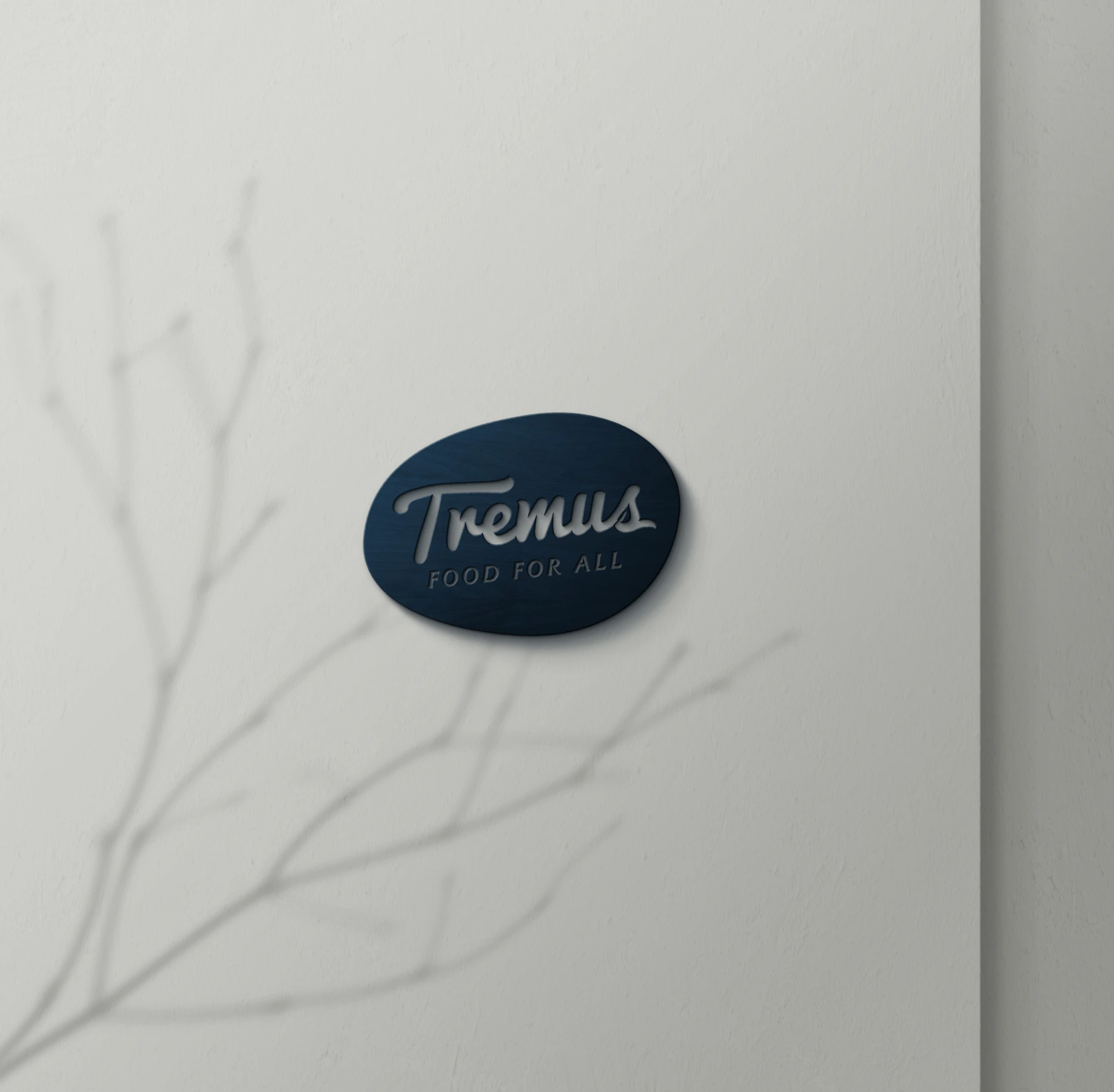 Aplicación del logotipo Tremus Food for All en una placa azul oscura sobre muro claro.