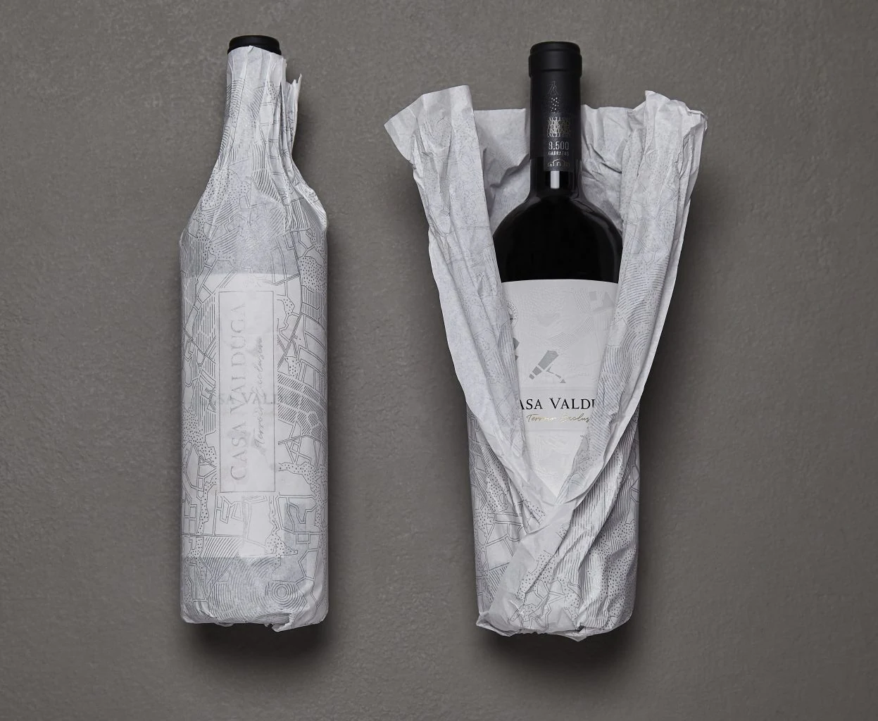 Botellas Casa Valduga con envoltorio de papel seda cartográfico.