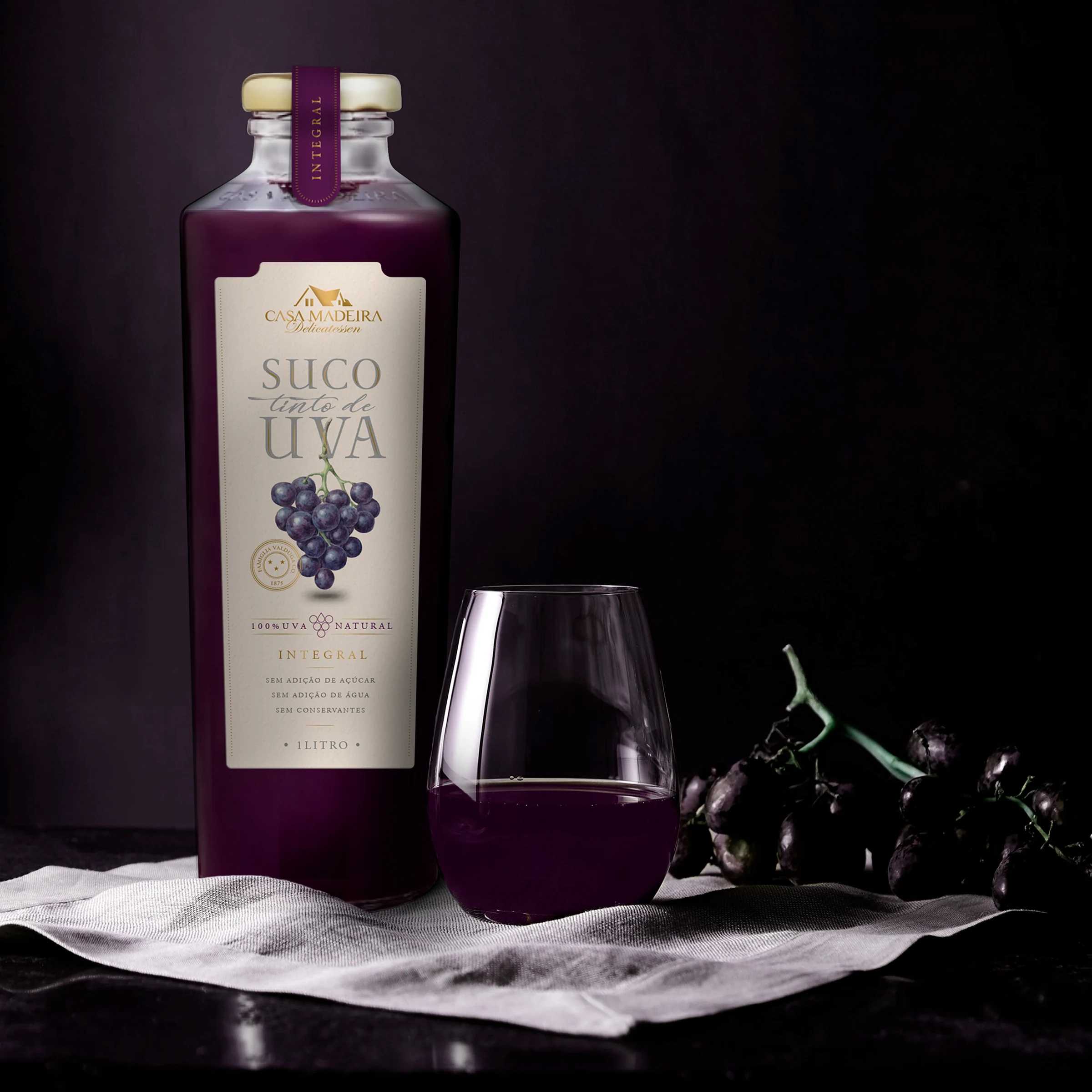Botella de Suco de Uva Casa Madeira junto a un vaso y uvas.
