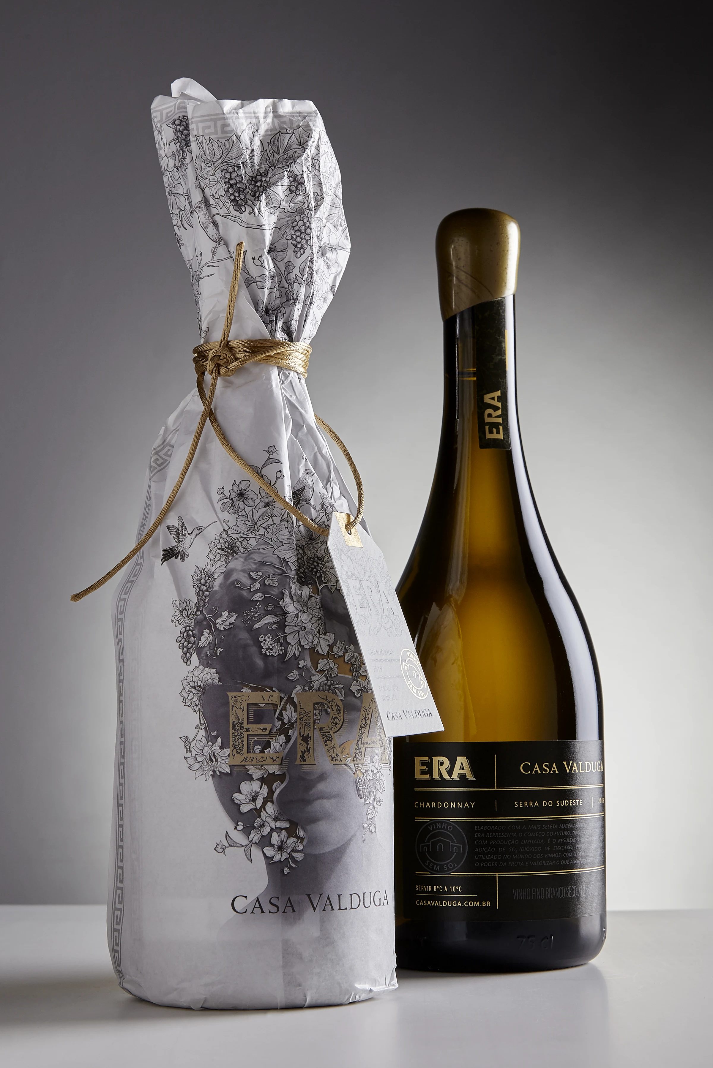 Botella ERA y su envoltorio ilustrado fotografiados sobre fondo claro.