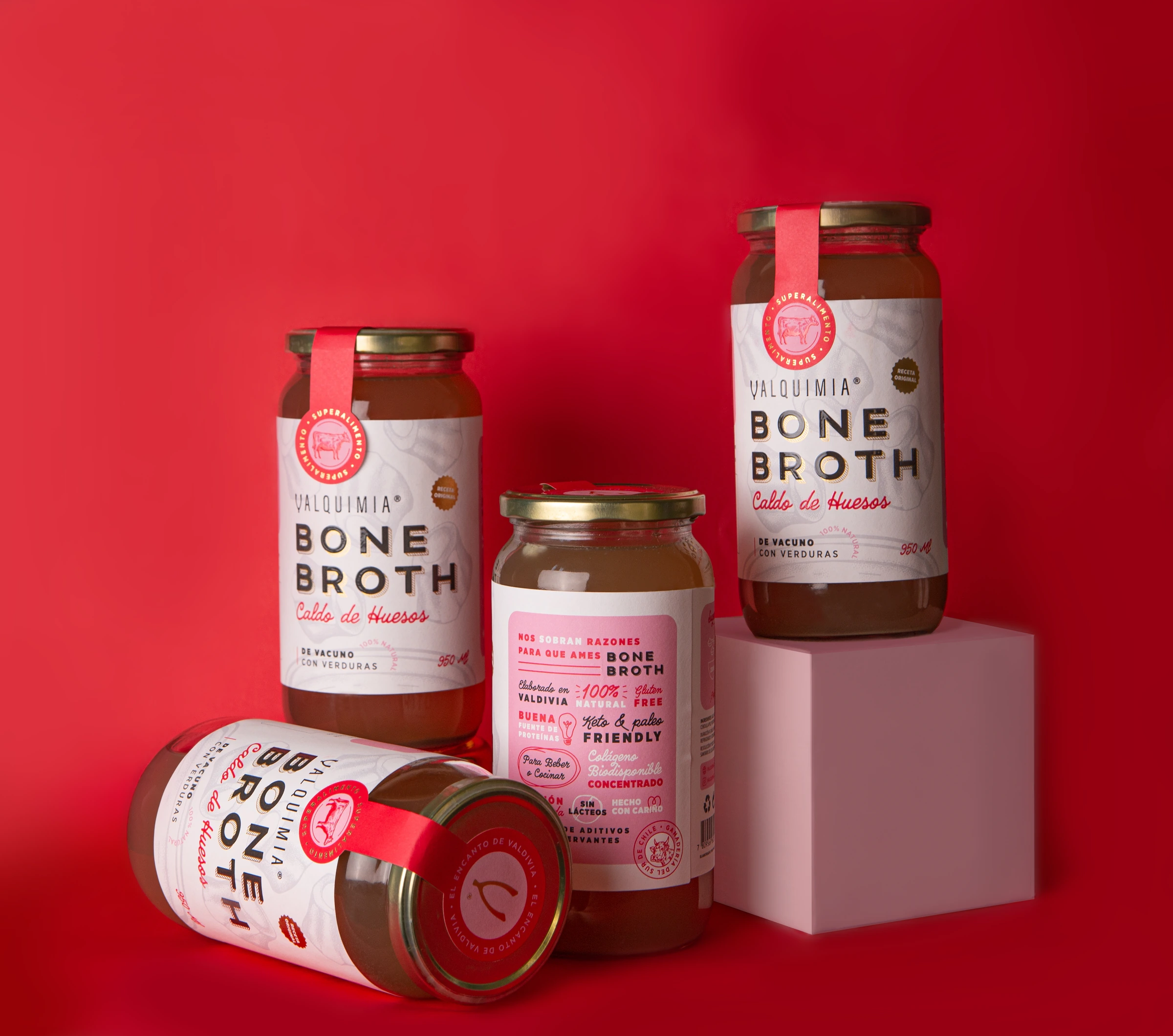 Conjunto de frascos Valquimia Bone Broth sobre fondo rojo, con distintas escalas y posiciones.