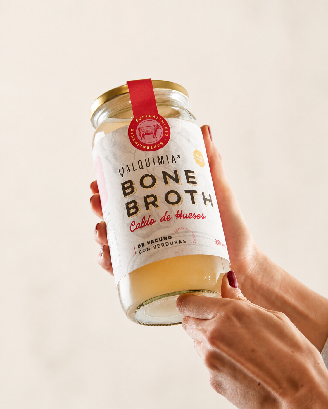 Frasco de Valquimia Bone Broth sostenido con ambas manos, mostrando la etiqueta completa.