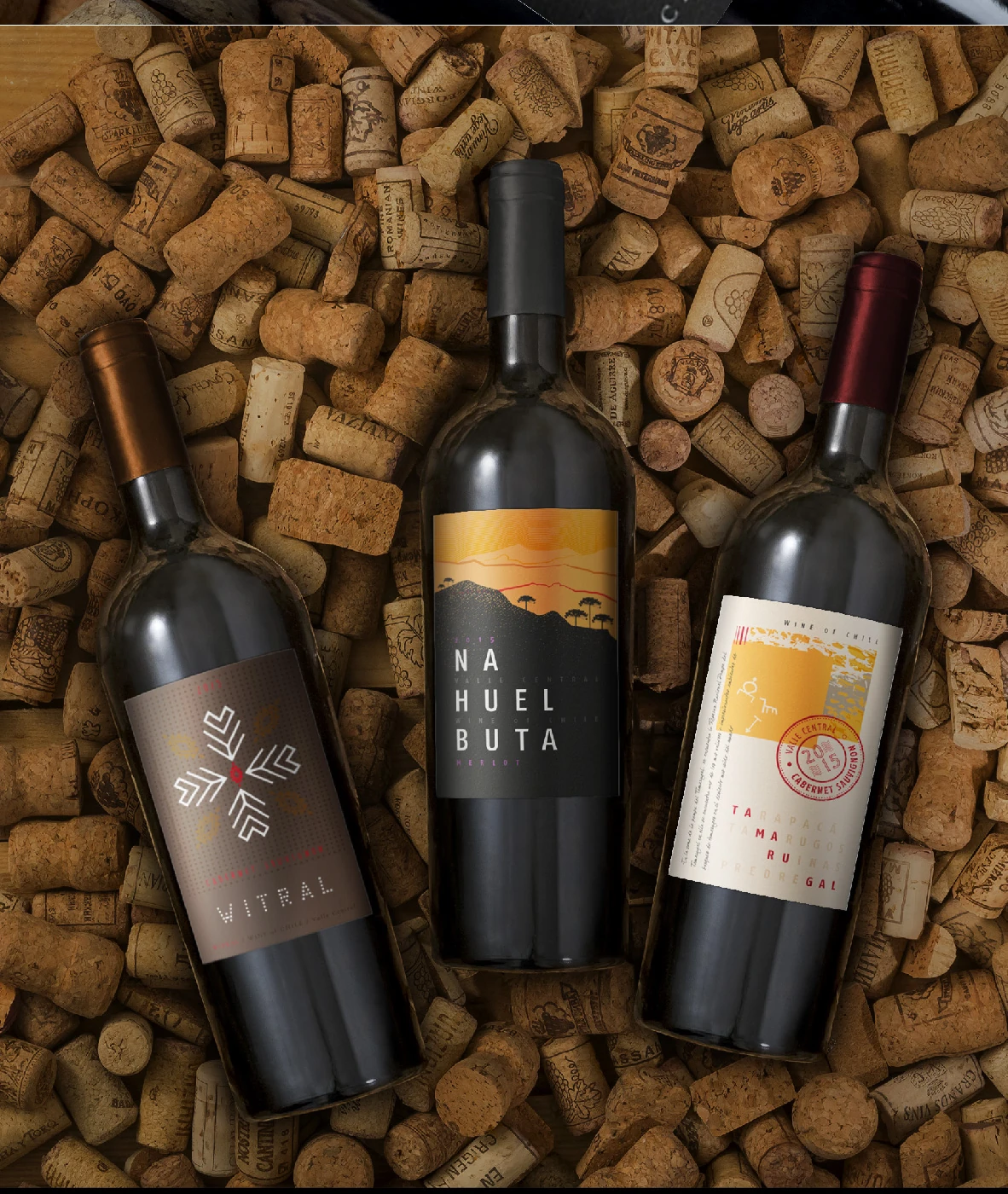 Tres botellas de una serie de etiquetas desarrolladas para Ventisquero sobre una superficie de corchos.