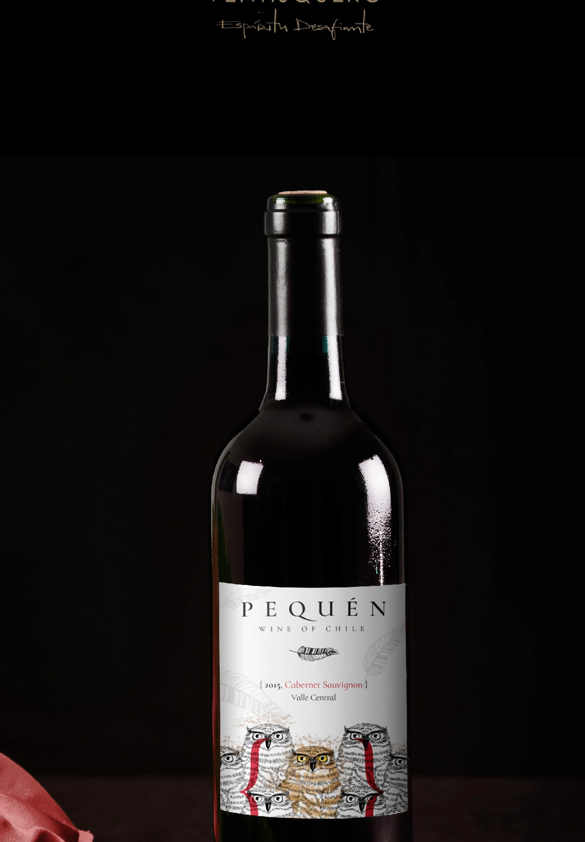 Botella Pequén fotografiada sobre fondo oscuro con tela roja.