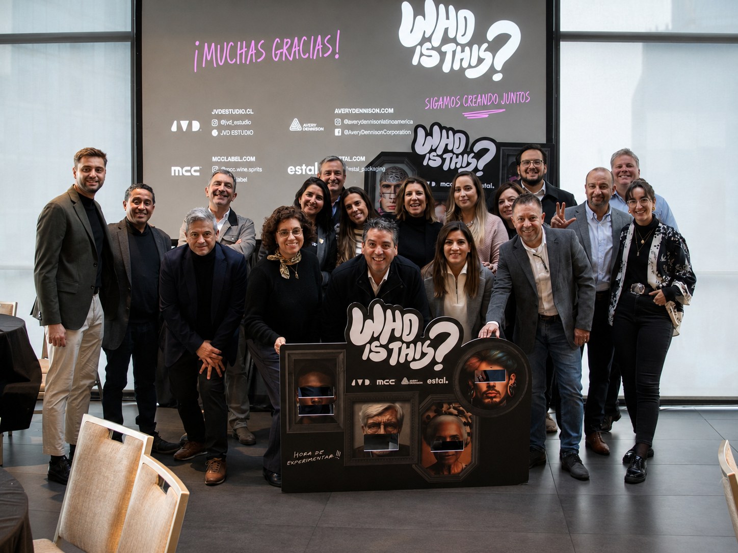 Equipo completo posando frente al backdrop Who is this Muchas gracias al cierre del evento