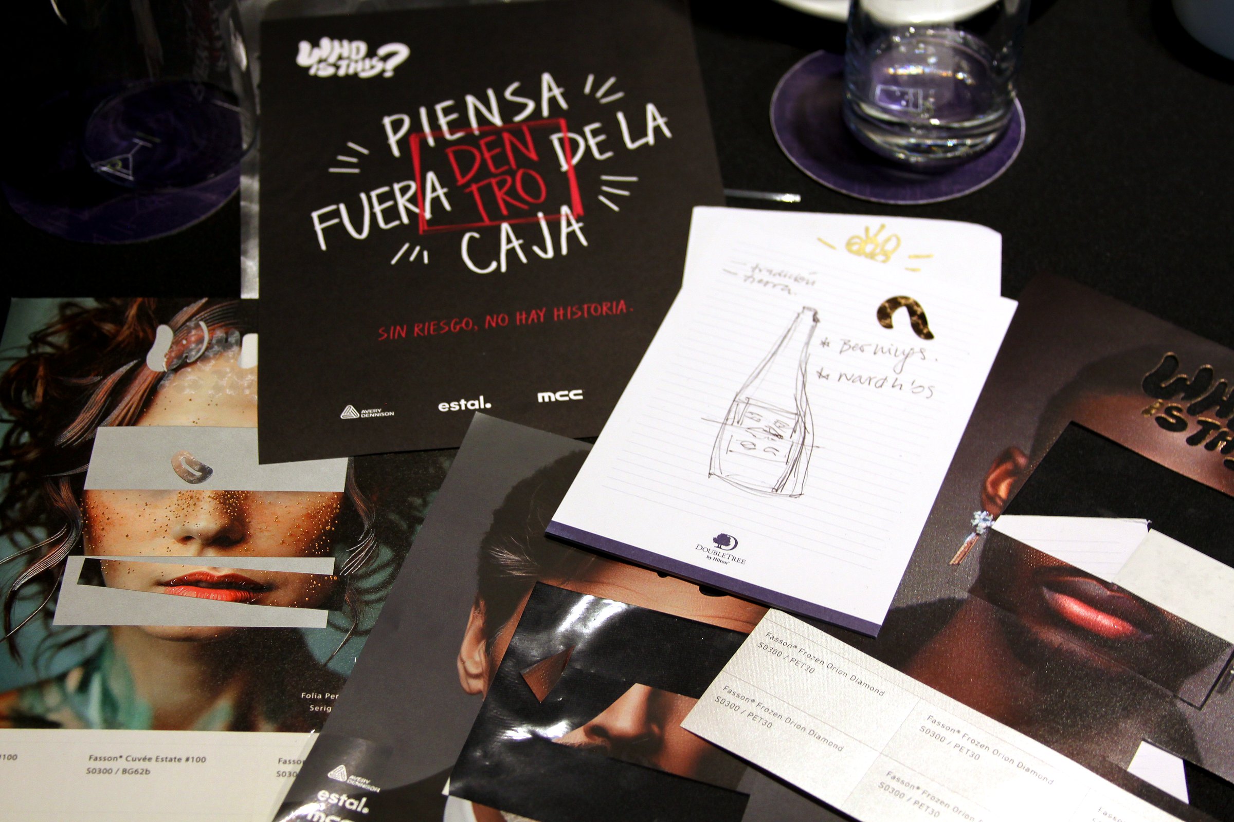 Mesa de trabajo con máscara, fotografías y materiales para intervenir botellas durante el taller WHO IS THIS
