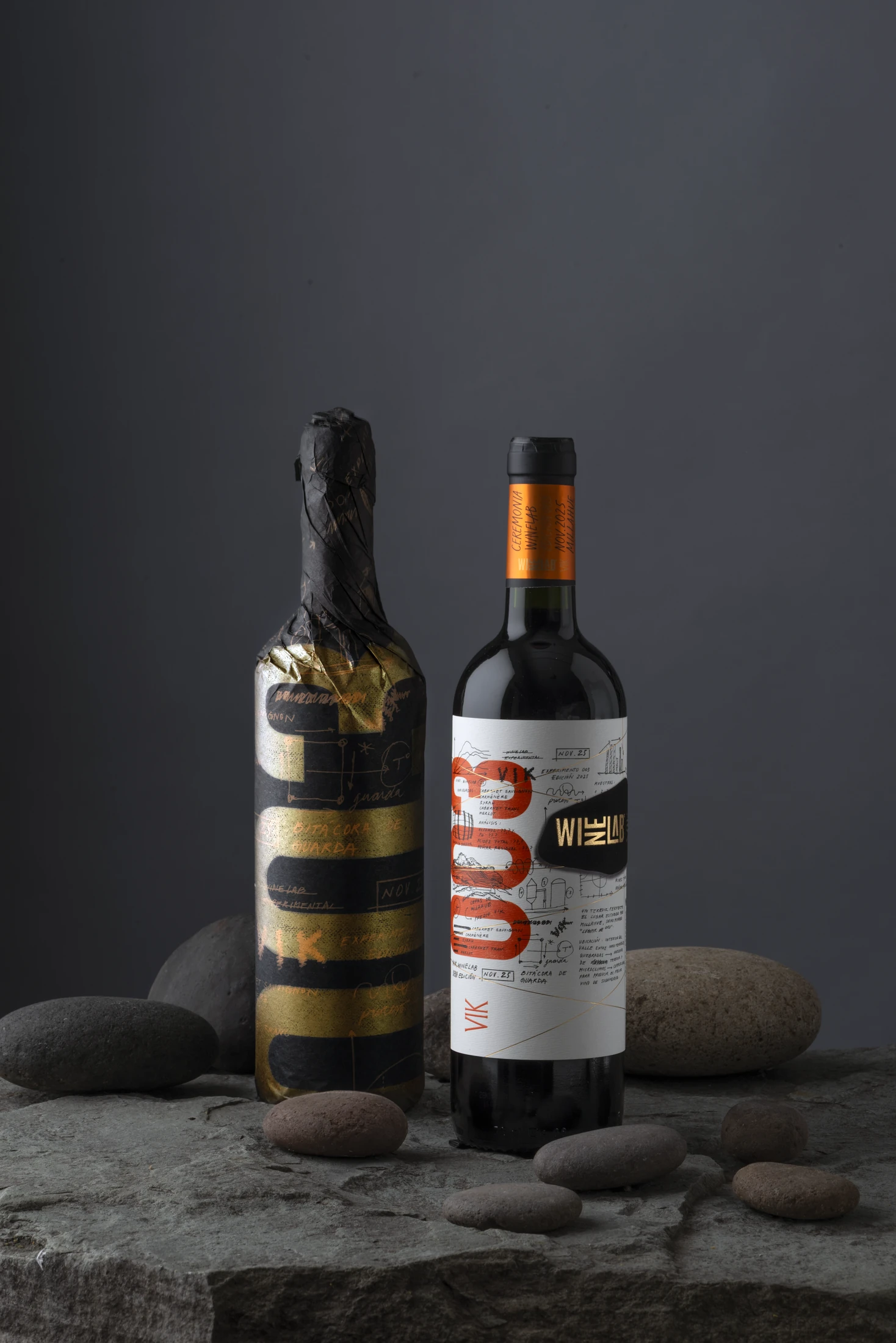 Edición 2025 de WineLab: la botella envuelta en papel negro y oro junto a la botella final de etiqueta clara con el numeral 003 en naranjo, sobre piedras.