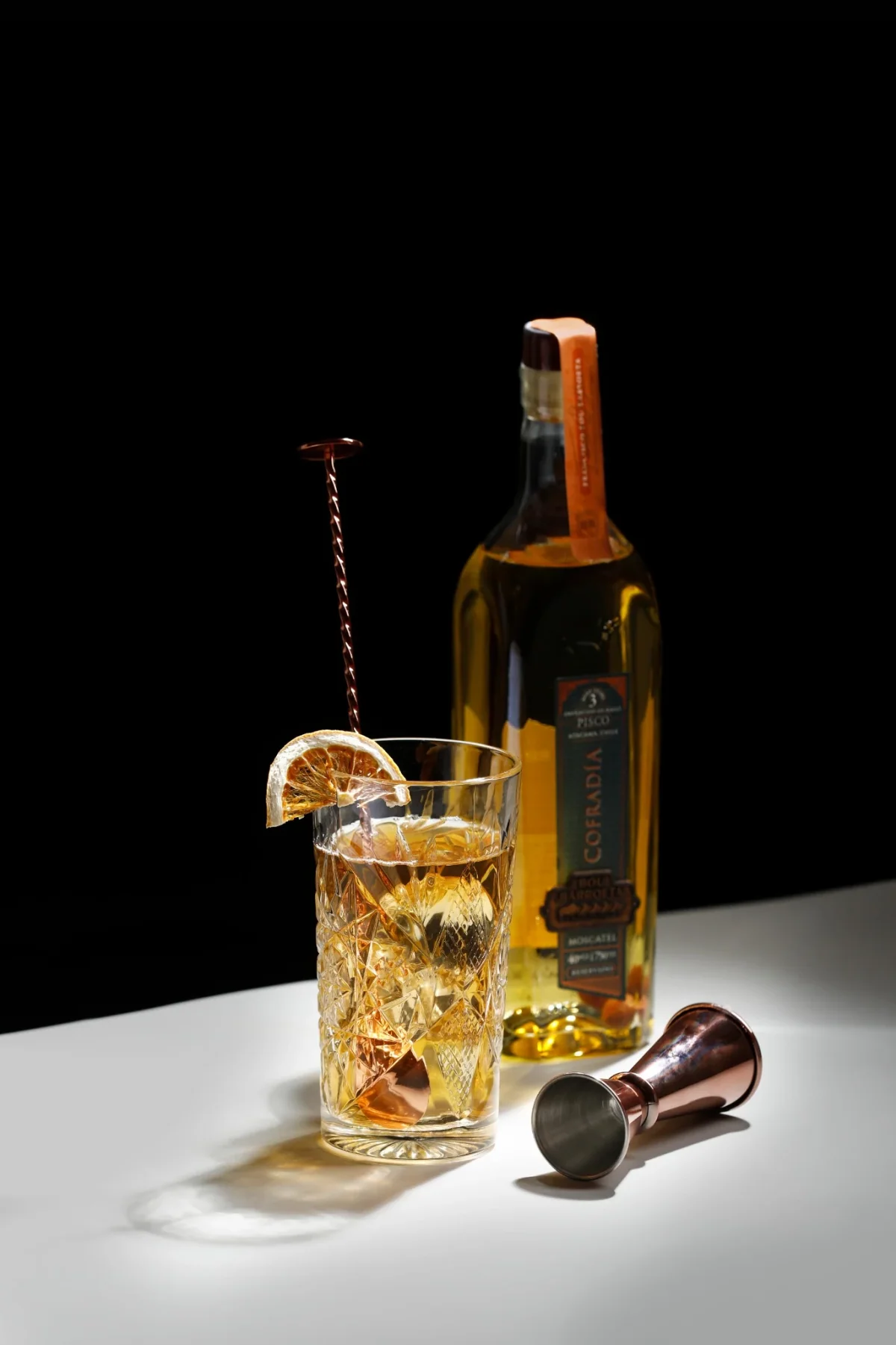 Cóctel preparado con pisco Cofradía de Bou Barroeta, con cítrico deshidratado y jigger de cobre.