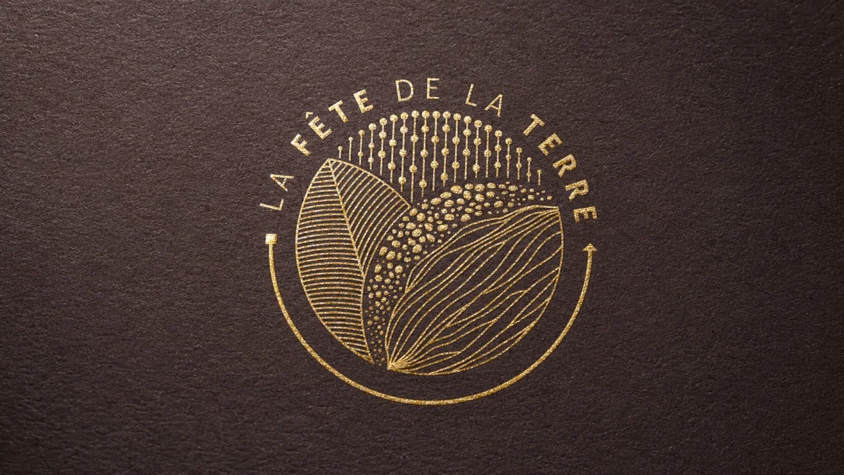 Emblema dorado de La Fête de la Terre estampado sobre una superficie café oscura con textura