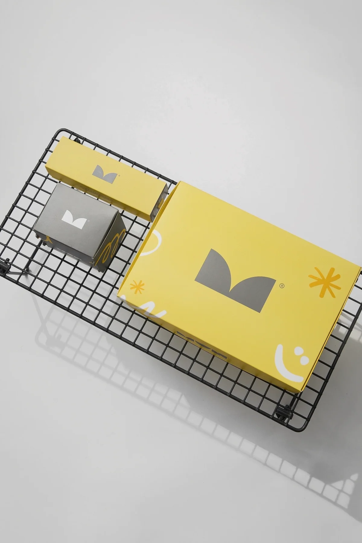 Sistema de packaging MUN en amarillo y gris, dispuesto sobre una estructura metálica negra.