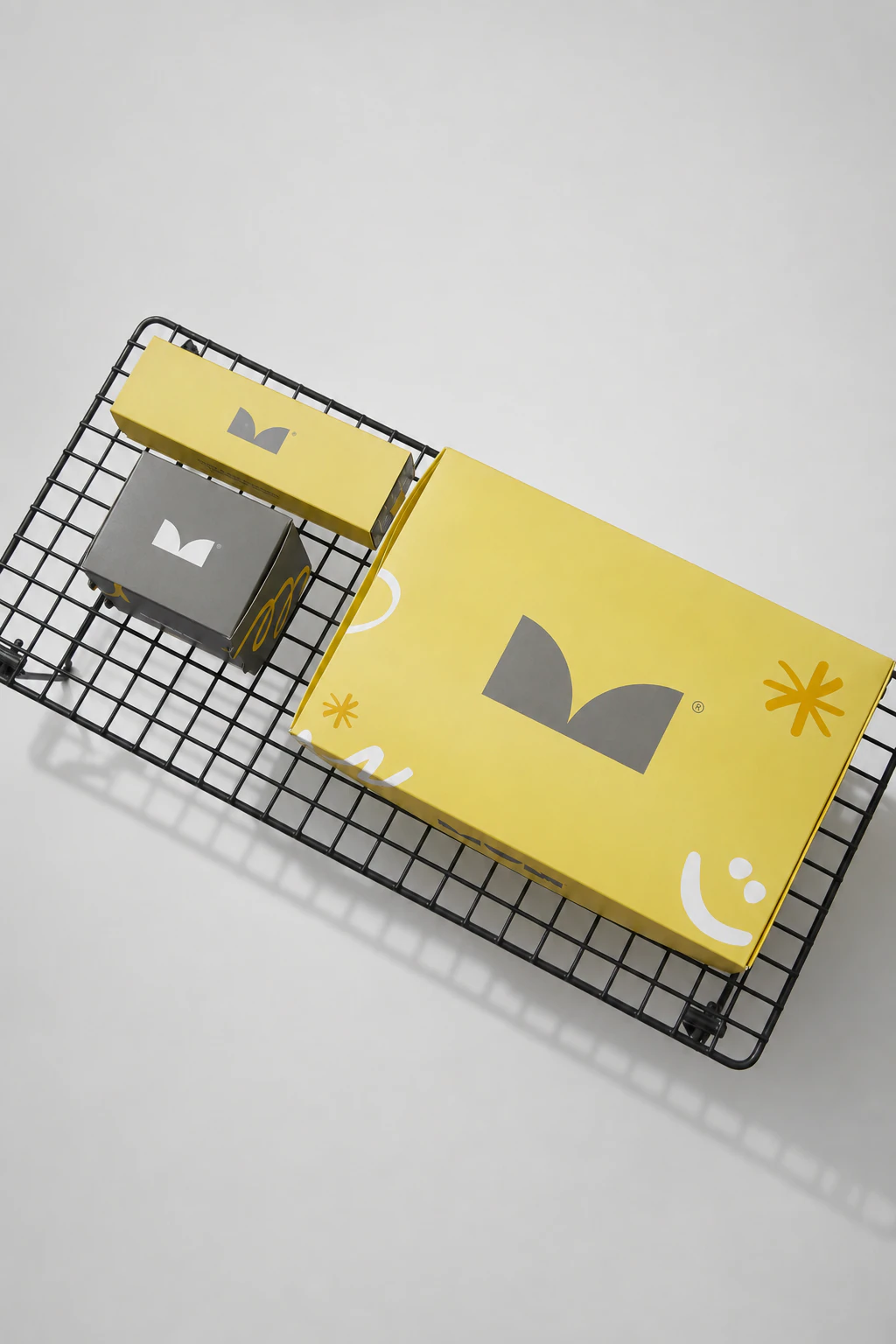 Sistema de packaging MUN en amarillo y gris, dispuesto sobre una estructura metálica negra.